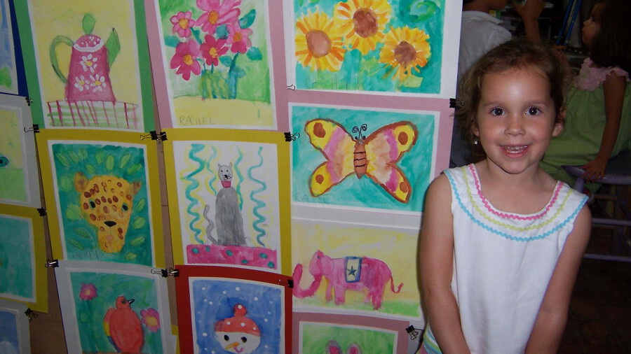 Heck as a child smiling in front of her artwork.